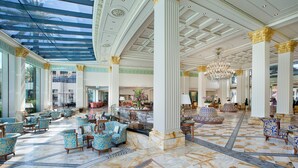 Un hall d’entrée spacieux, doté d’un sol en marbre, de fauteuils à motifs et de grandes colonnes.