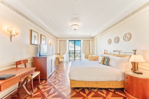 Habitación de hotel con cama, escritorio, silla, televisión y vistas al exterior.