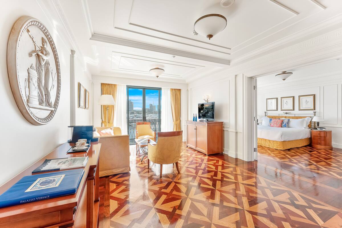 A hotel room with a large window, a bed, a desk, and a chair.