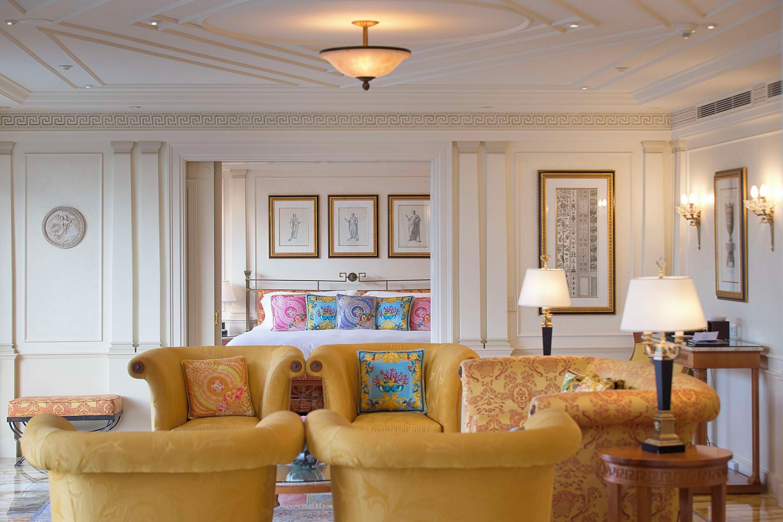 A hotel room with a bed, two armchairs, a side table, and a lamp.
