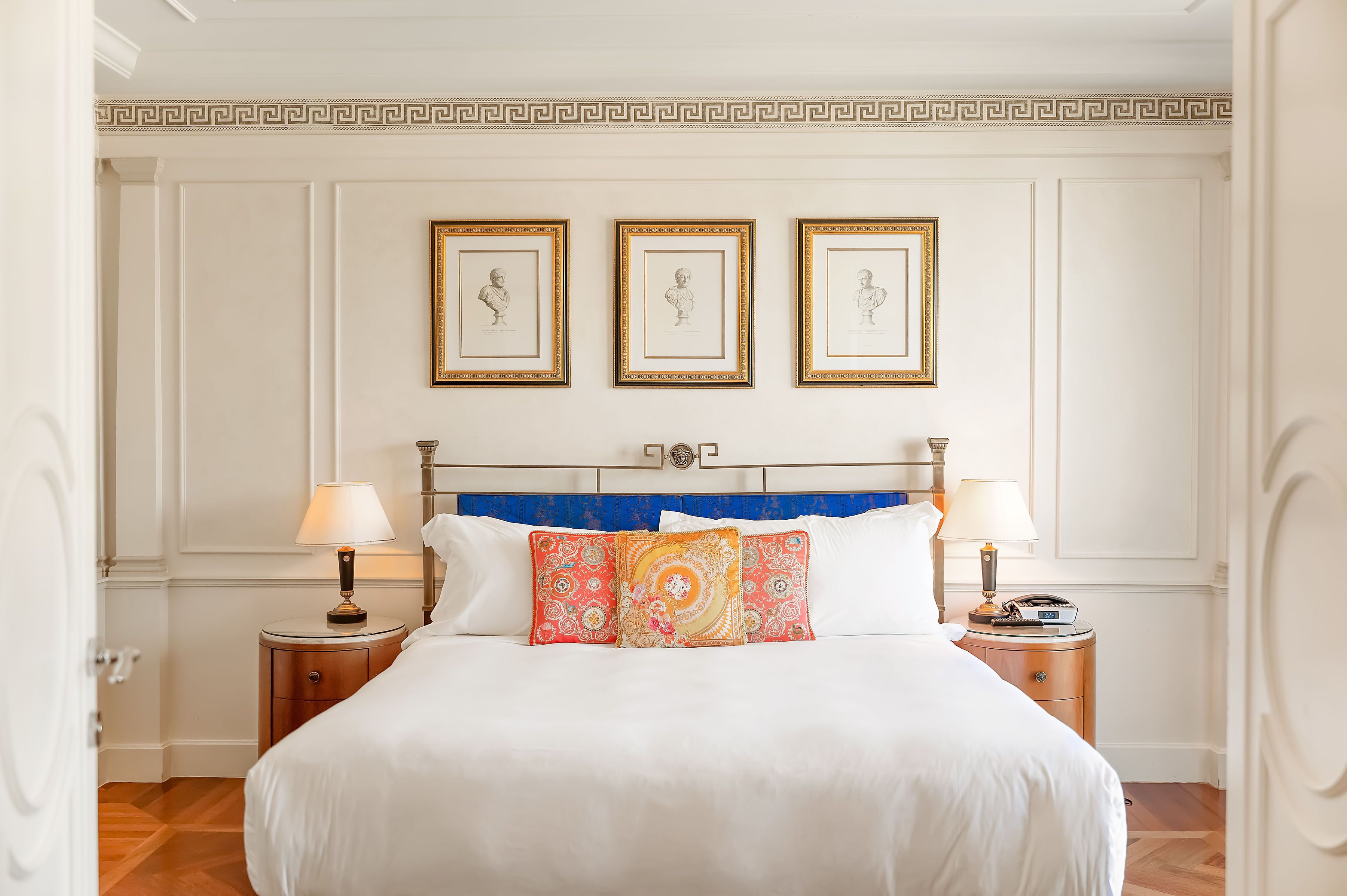 A neatly arranged bedroom with a large bed, two bedside tables, and three framed pictures on the wall.