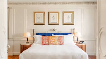 A neatly arranged bedroom with a large bed, two bedside tables, and three framed pictures on the wall.