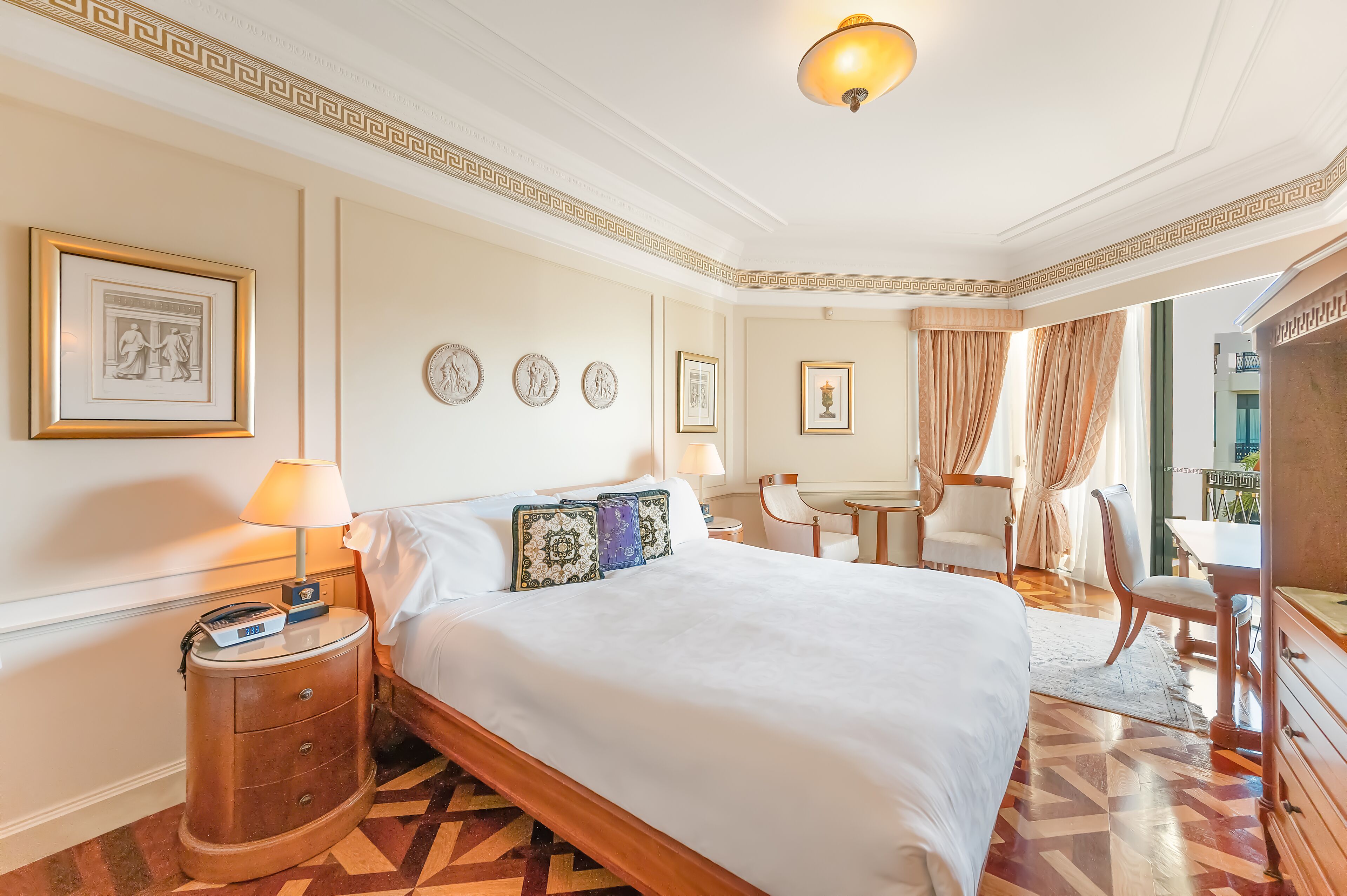 A hotel room with a large bed, bedside tables, a desk, and a chair.