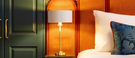 A hotel room with a bed, a nightstand with a lamp, and a decorative wall panel.