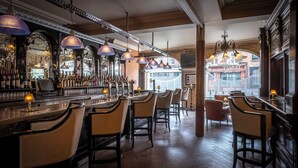 Zona de bar con diversas opciones de asientos, barra bien surtida y vista a la calle.