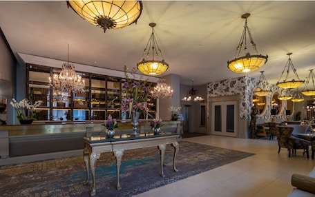 A spacious lobby with ornate chandeliers, a reception desk, and a large window with a view of the interior.