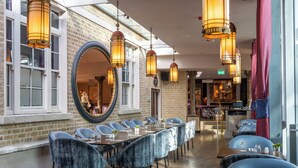 Un restaurante con una larga mesa, sillas azules y faroles colgantes.