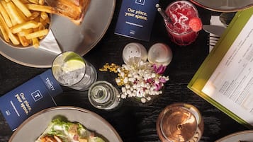 Una mesa dispuesta con diversos platos, incluyendo una ensalada, sándwiches y una bebida, junto con un menú y algunos adornos.
