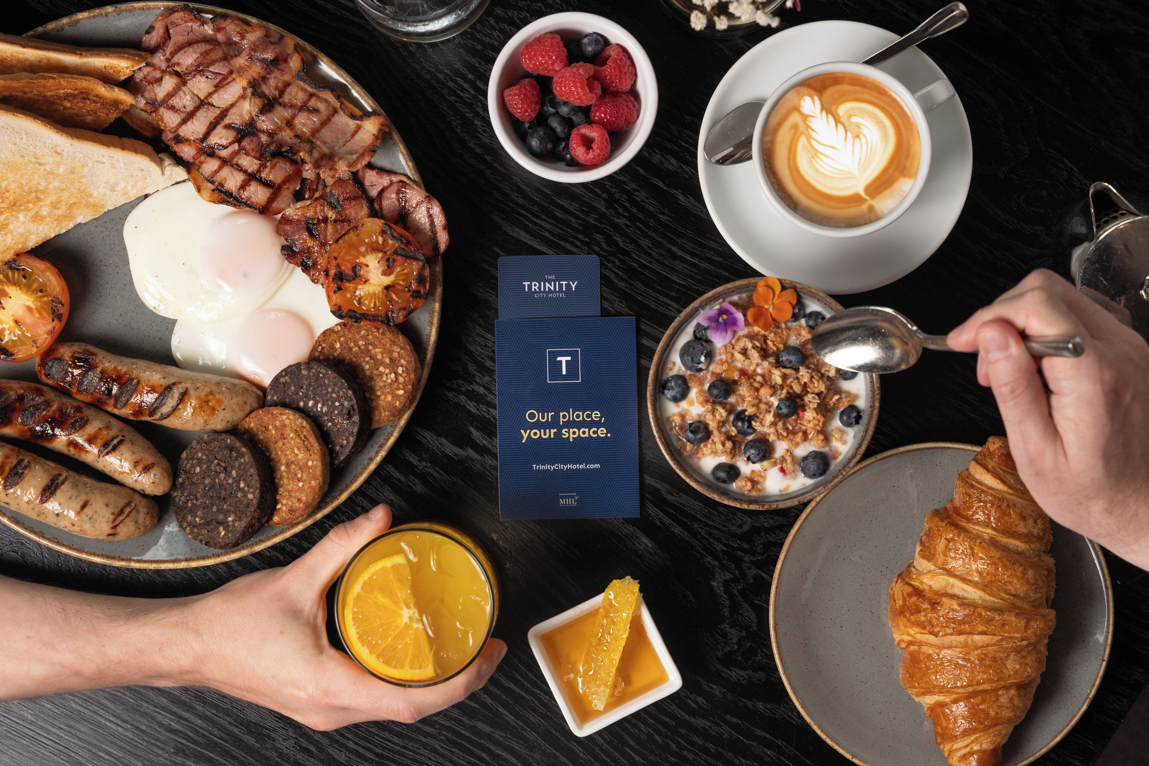 Una mesa con variedad de desayuno: tostadas, huevos, salchichas y un croissant.