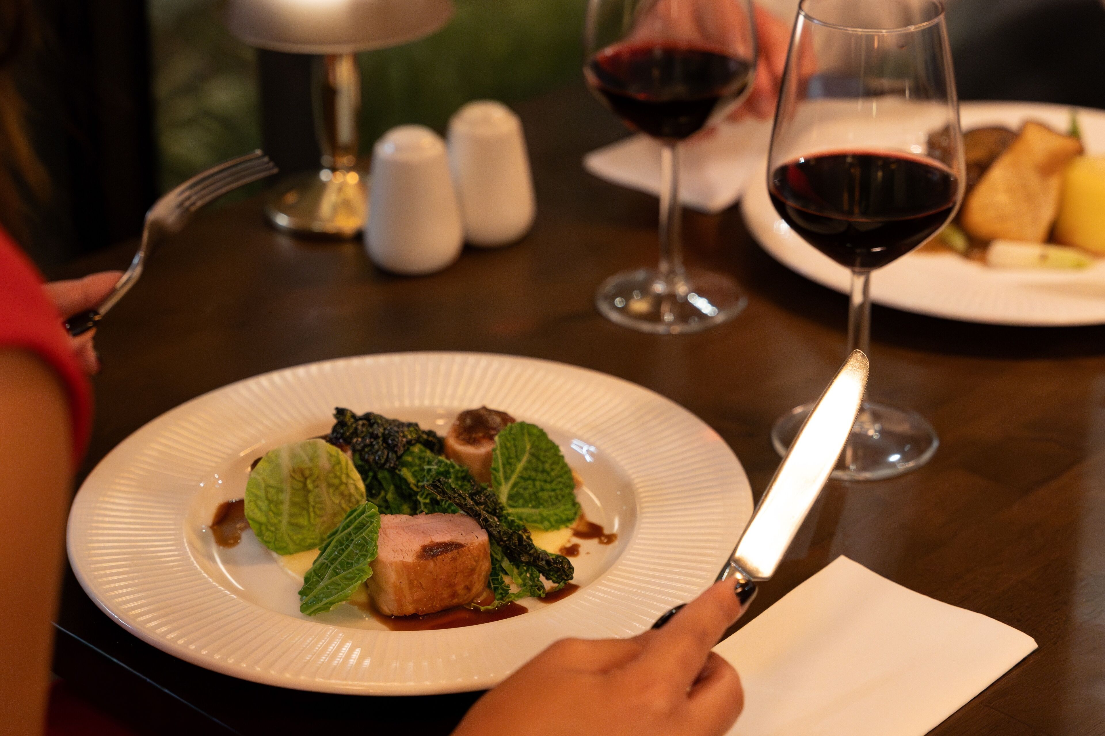 A dining table with a plate of food, a wine glass, and a fork.