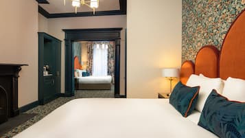 A hotel room with a large bed, a nightstand with a lamp, a dresser, and a door leading to another room.