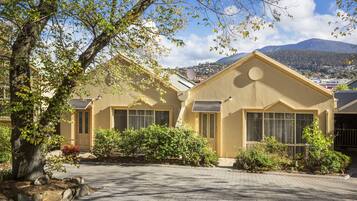 Keltainen talo, jossa on ajotie, ja taustalla näkyy vuori.