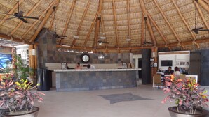 A reception area with a thatched roof, a reception desk, a clock, and a seating area with chairs. - Park Royal Homestay Los Cabos (San José del Cabo)