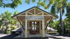 En byggnad med skylten ”Sands Resort”, en överbyggd entré och en informationsskylt.