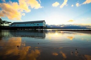 A waterfront building with a flat roof, multiple windows, and a pier extending into the water. - Port Douglas Sands Resort (Port Douglas)