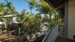 A resort with a pool, palm trees, and a wooden deck. - Marlin Cove Resort (Trinity Beach)