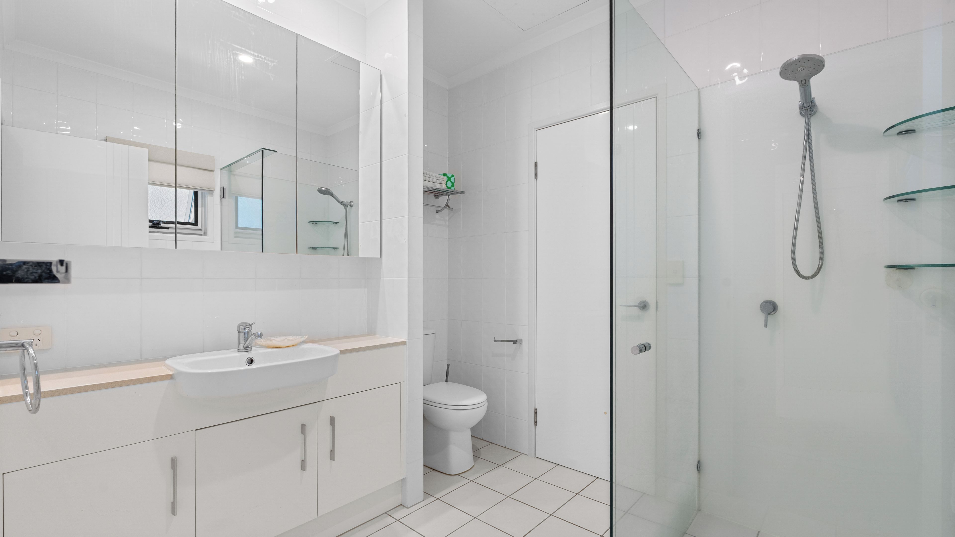 A modern bathroom with a glass shower enclosure, a white sink, and a toilet.