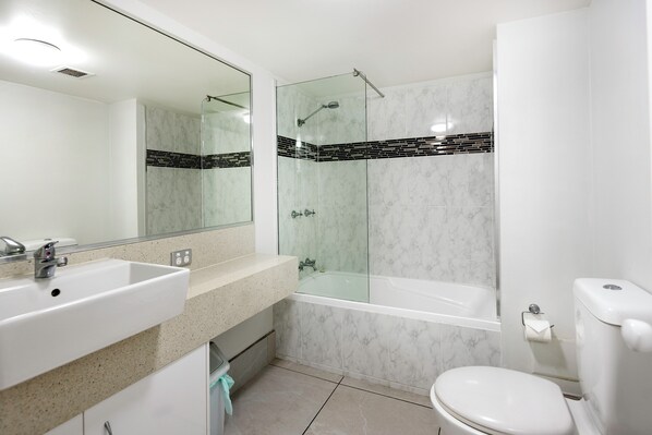 A modern bathroom with a glass-enclosed shower, a white sink, and a toilet. - Marlin Cove Resort (Trinity Beach)