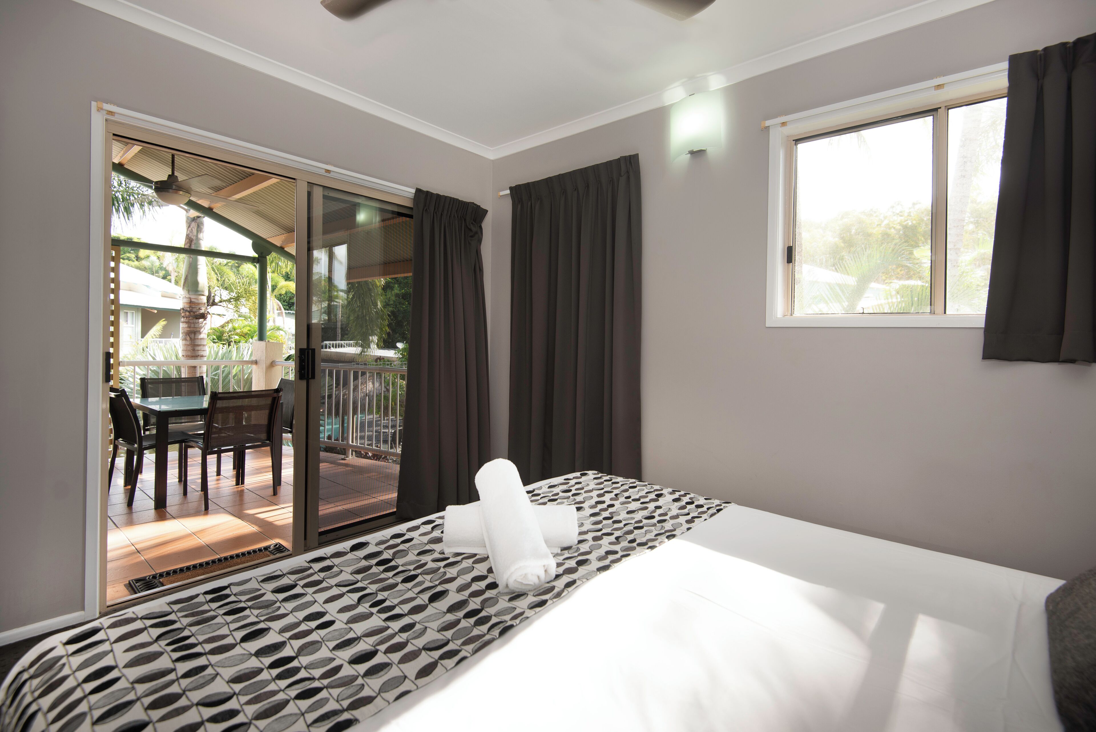 Une chambre d’hôtel avec un lit, une vue sur la terrasse extérieure et une porte-fenêtre coulissante donnant accès à la terrasse.