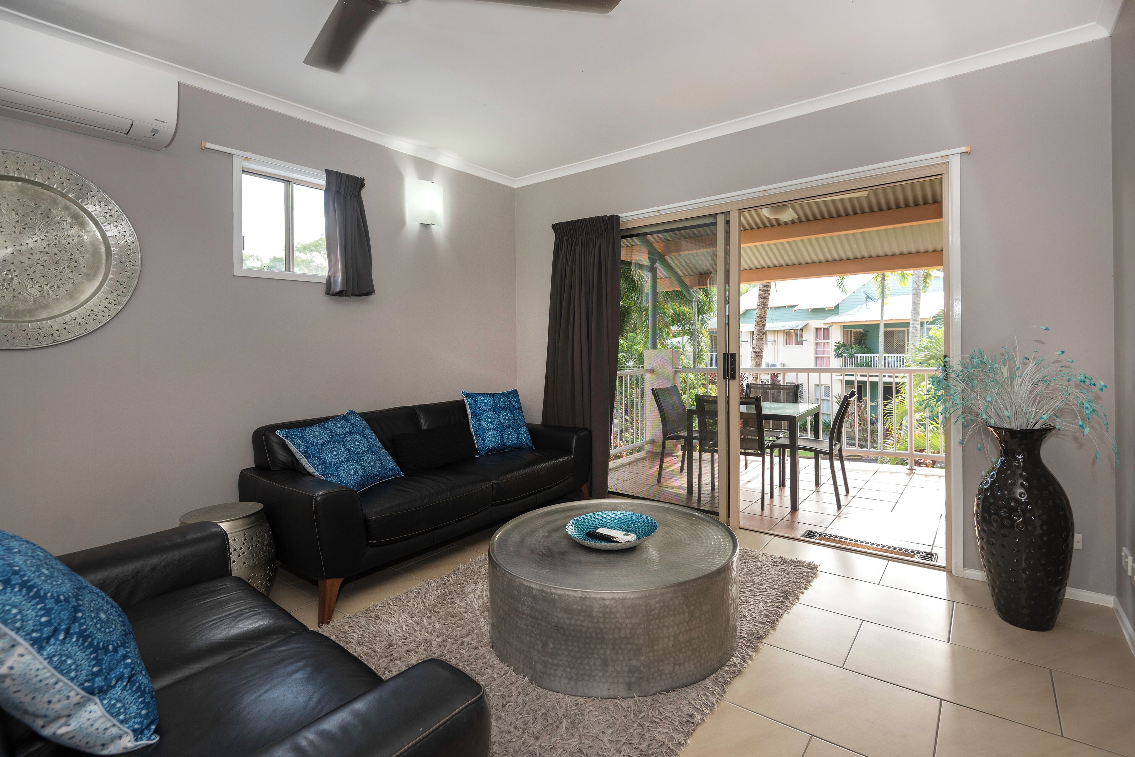 A modern living room with a black leather sofa, a round coffee table, and a large vase.