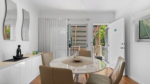 Un comedor moderno con una mesa de vidrio, sillas de cuero y vistas a un balcón con barandilla de madera.