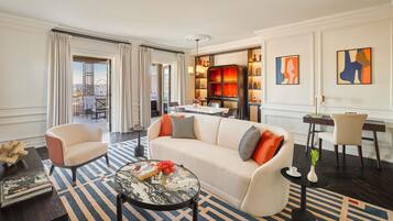 Una habitación de hotel moderna con sofá, sillones, zona de comedor y obras de arte en las paredes.