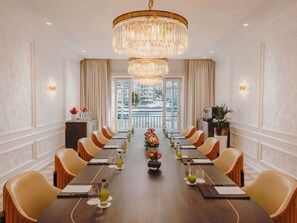 A formal dining room with a long table, chairs, a chandelier, and a view of a marina.