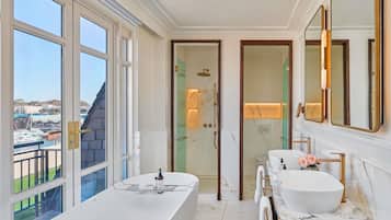 A modern bathroom with a large bathtub, two sinks, and a shower.