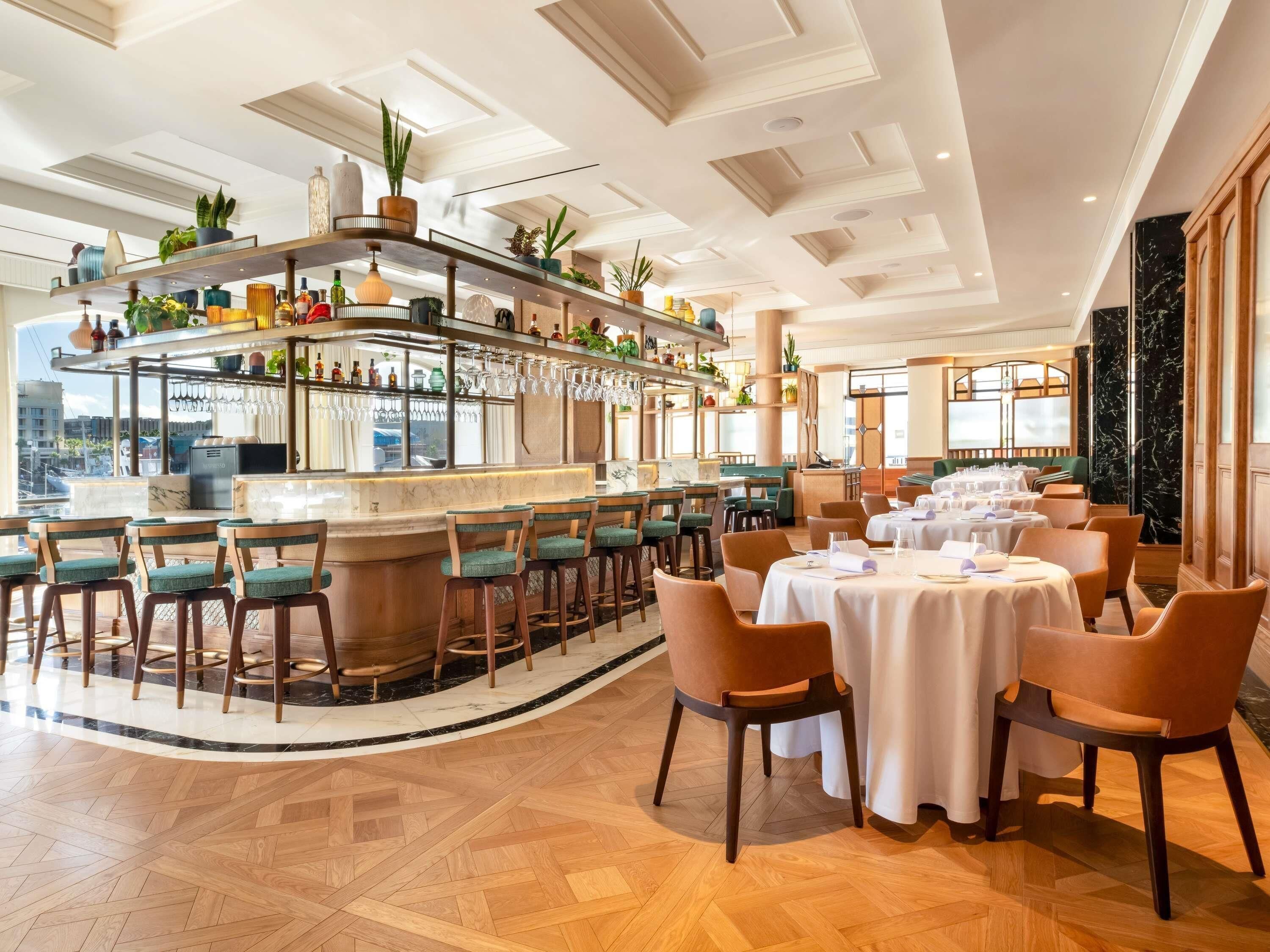 A restaurant with a bar area, multiple seating options, and a view of the city.