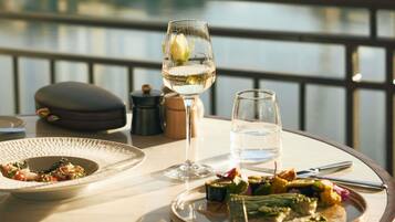 A dining table with plates of food, a wine glass, and a water glass.