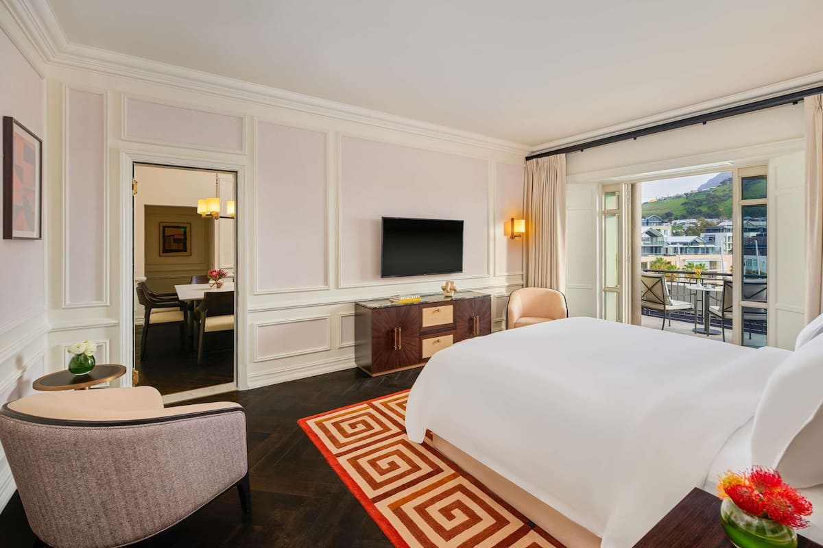 Habitación de hotel con una cama grande, un escritorio, una silla, un televisor y un balcón con vistas.