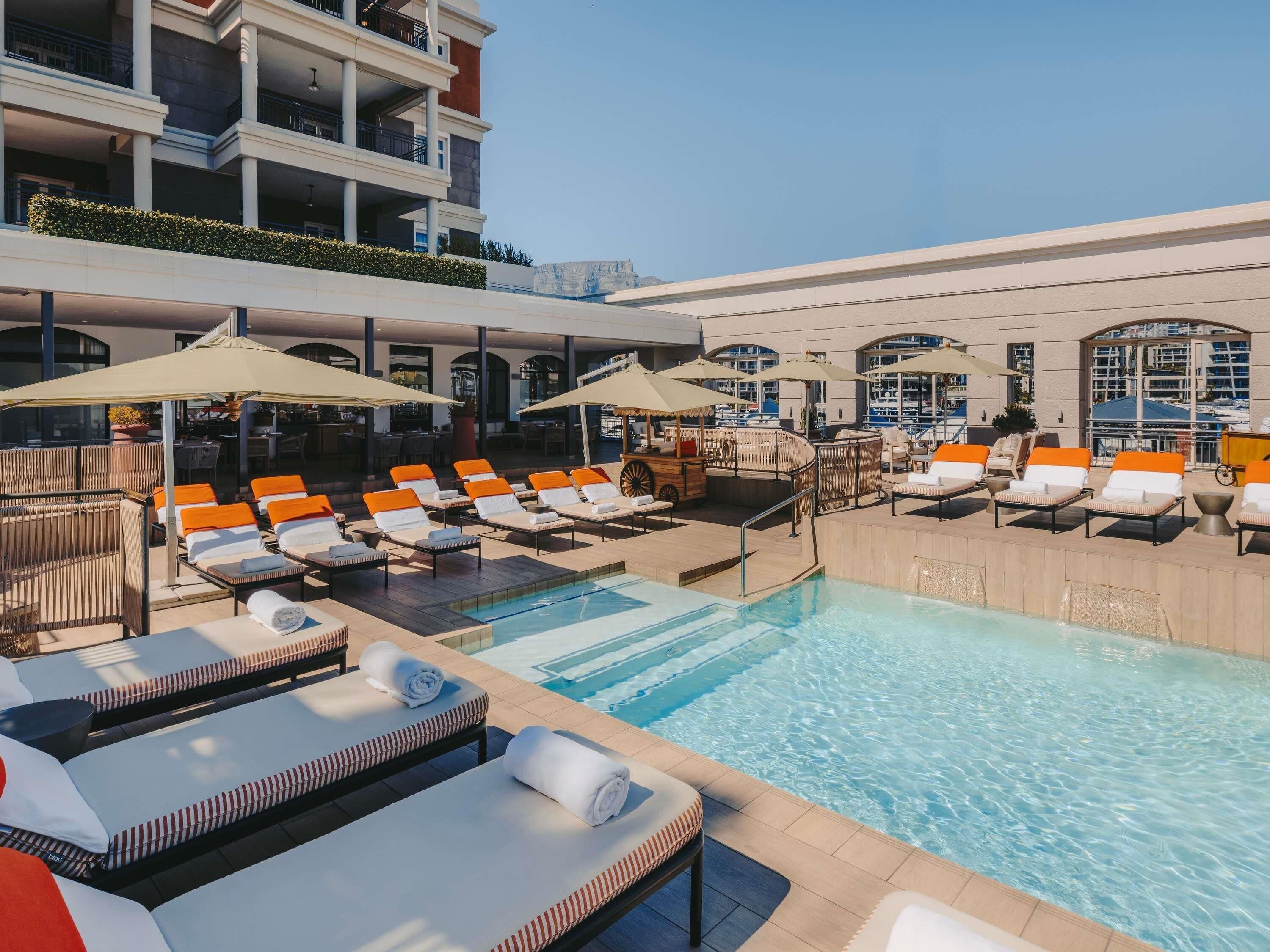 A pool area with sun loungers, umbrellas, and a bar area.