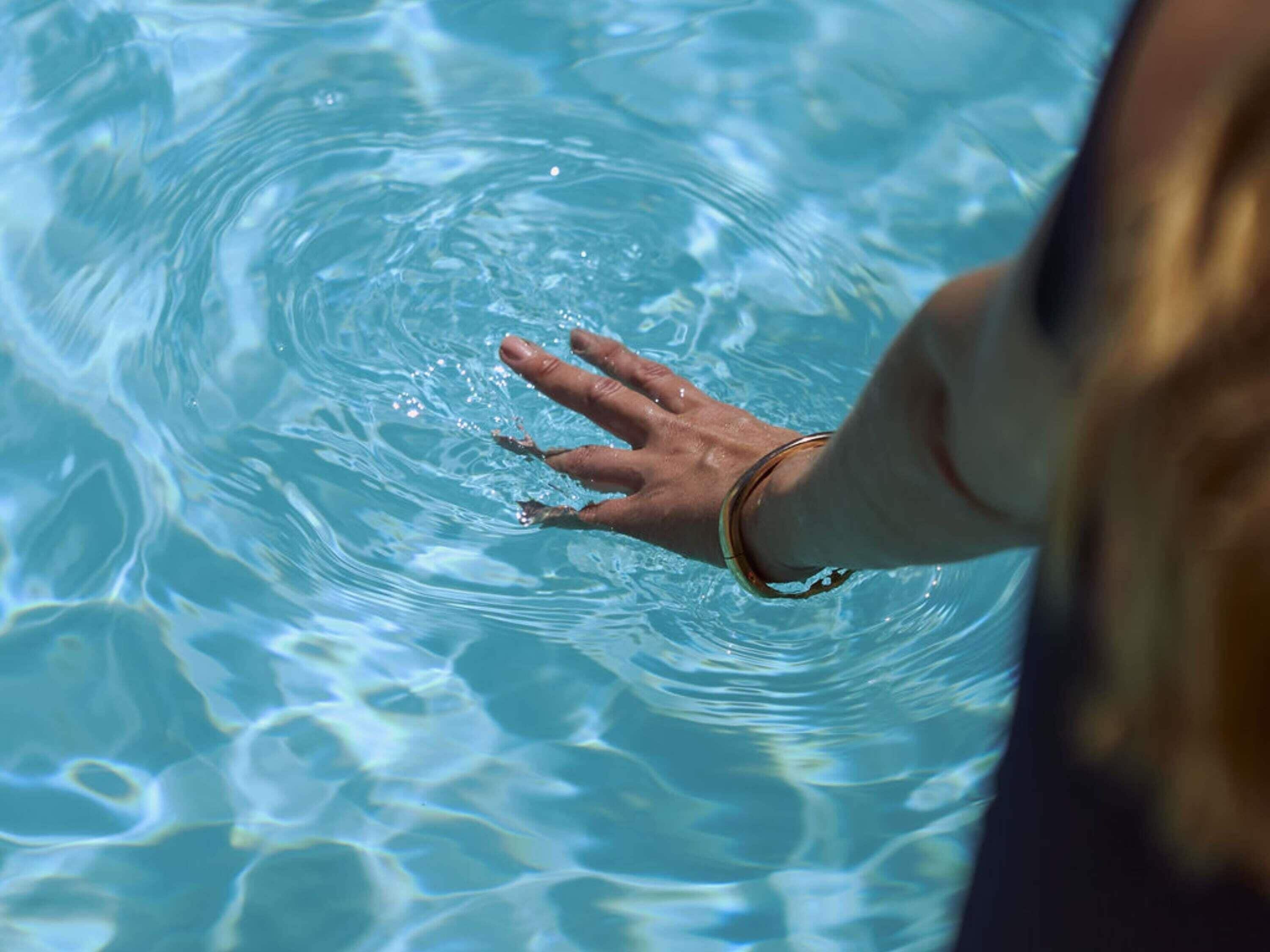 Una mano sumergiéndose en agua cristalina azul.