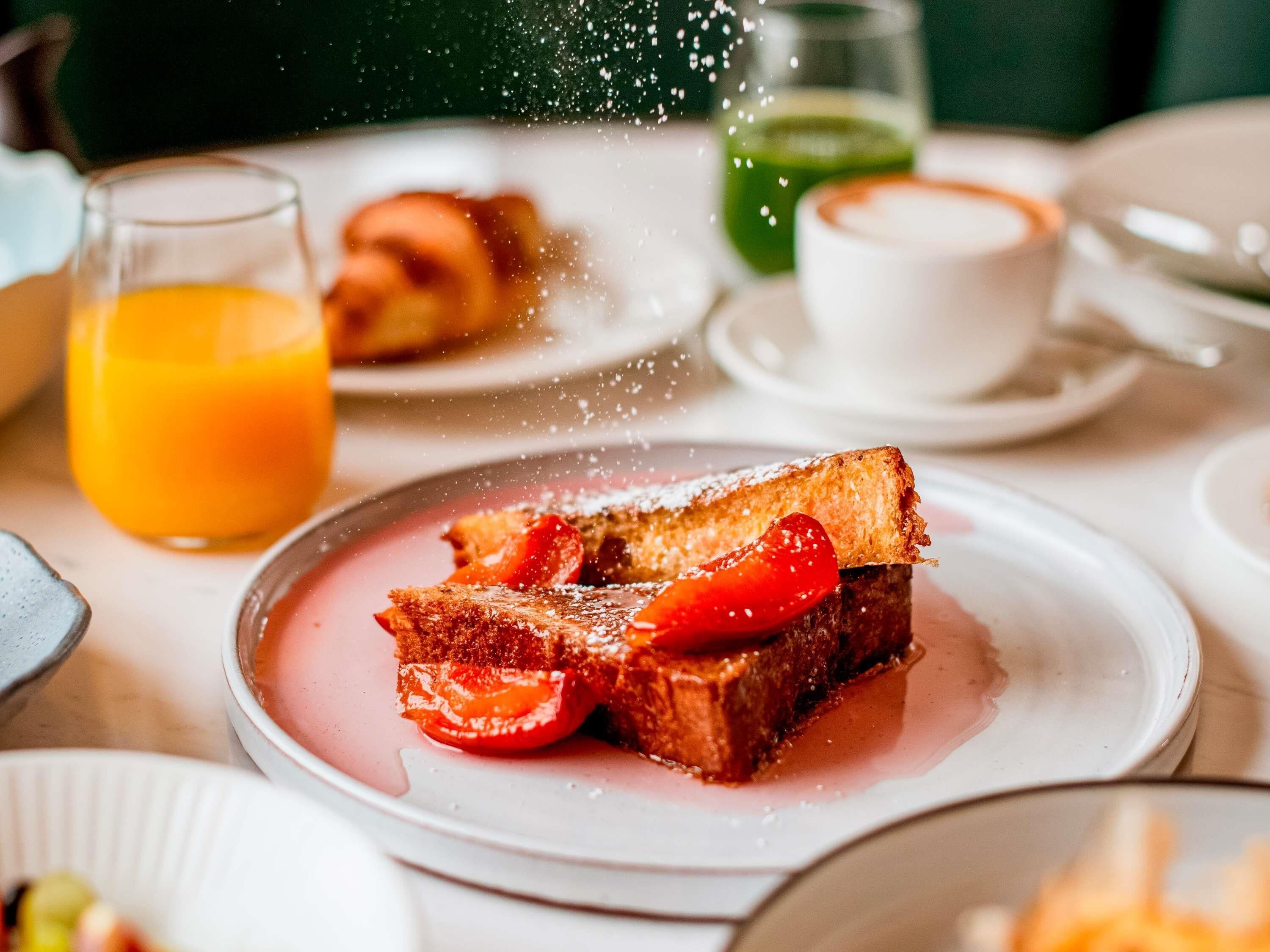 A breakfast setting with toast, strawberries, and a glass of orange juice.