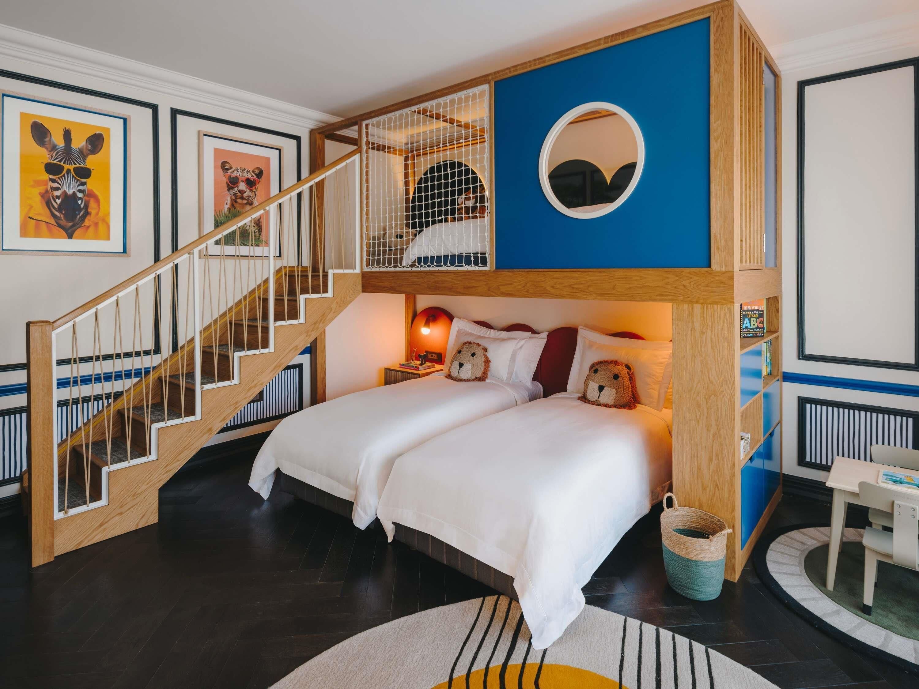 A room with a bunk bed, a wooden staircase, a round mirror, and framed animal artwork.
