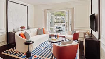 Una sala de estar moderna con un sofá, sillones, una mesa de centro y vistas a la ciudad a través de grandes ventanales.