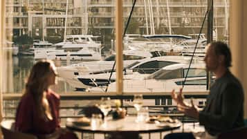 Un comedor con vista a un puerto deportivo y edificios al fondo.