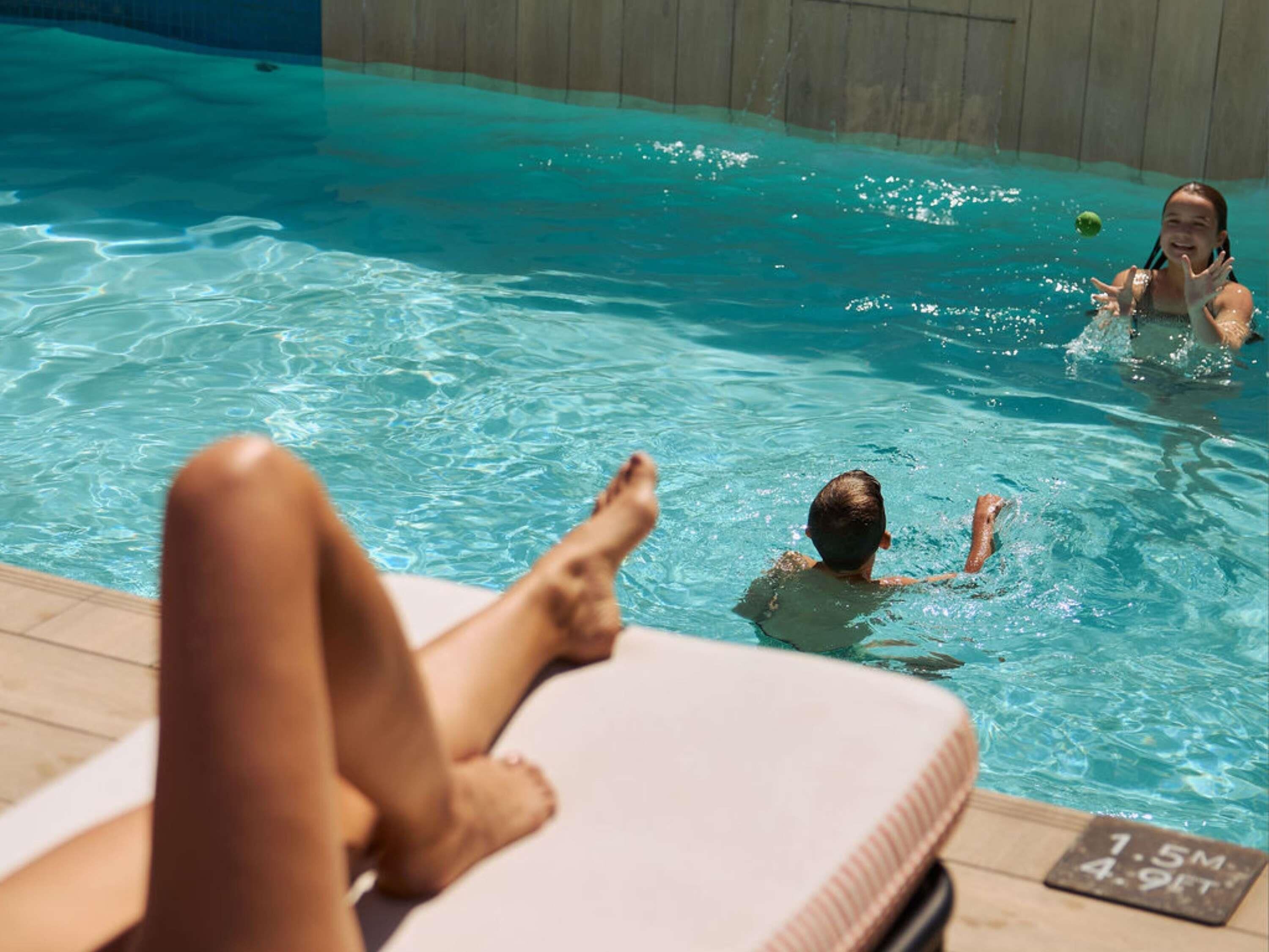 Una piscina al aire libre, sombrillas, sillones reclinables de piscina