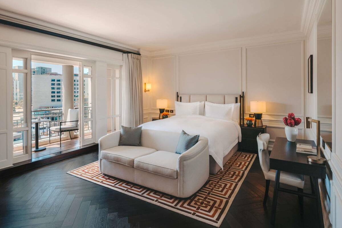 Una habitación de hotel con una cama grande, un sofá, una mesa de comedor y vistas a la ciudad.