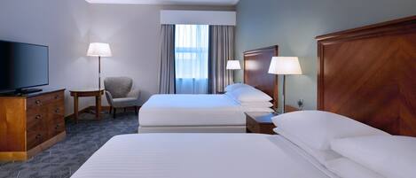 A hotel room with a large bed, a TV, a desk, and a chair.