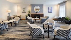 A hotel lobby with a fireplace, multiple seating areas, and a large mirror on the wall. - Delta Hotels Bexleyheath (Bexleyheath)