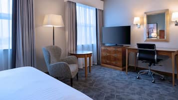 Une chambre d’hôtel équipée d’un lit, d’un bureau, d’une chaise, d’une télévision et d’un miroir.