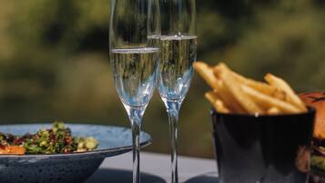 Deux verres d’eau sur une table, avec une assiette de nourriture et un panier de frites.