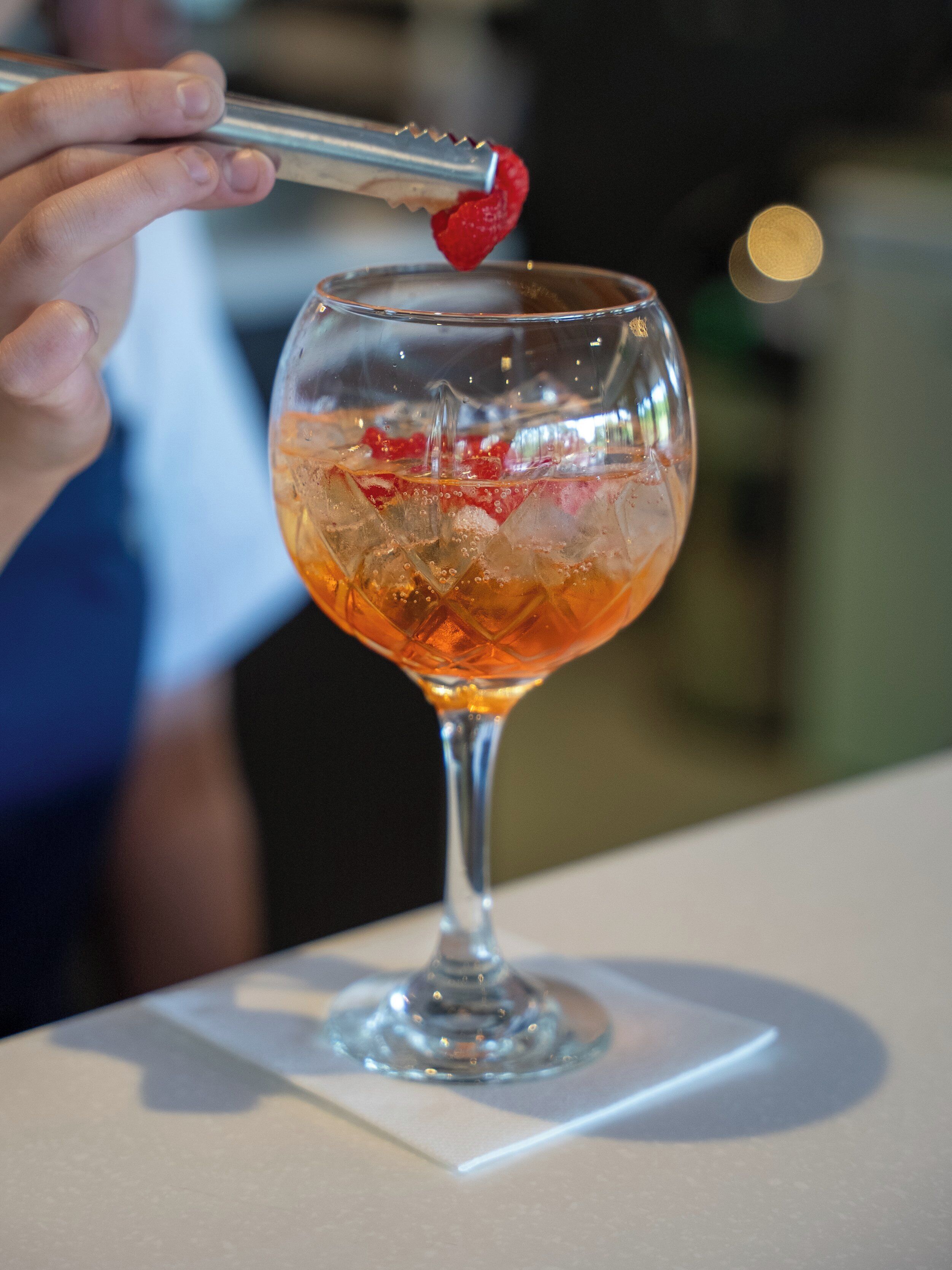 Ein Cocktail im Stielglas mit Eiswürfeln und Erdbeere.