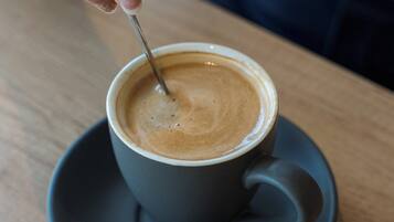 A hand stirring a cup of coffee on a saucer.