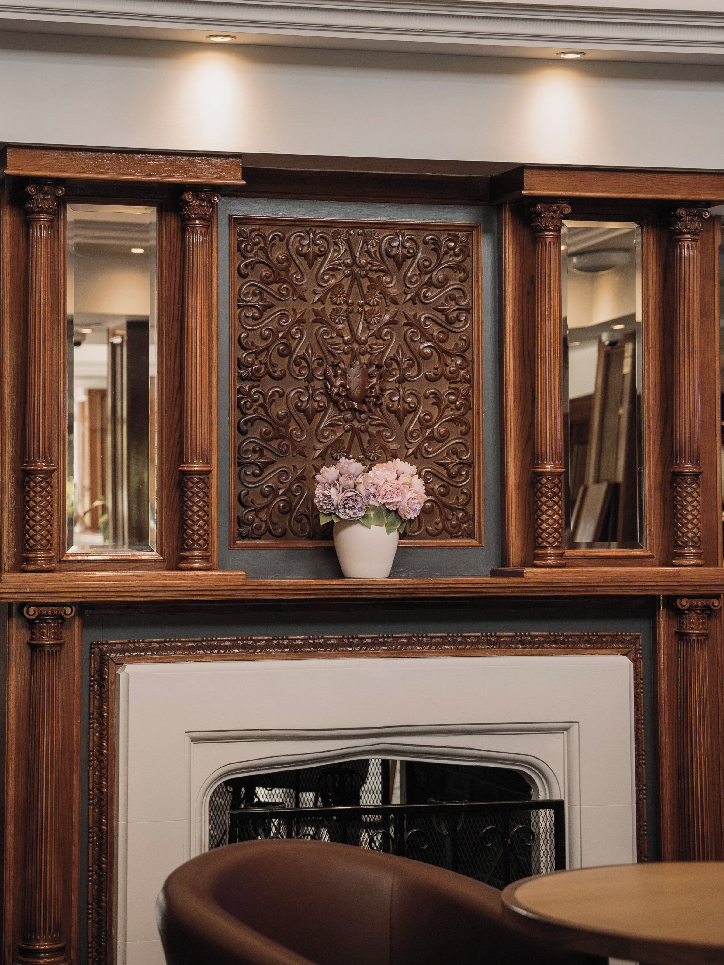 A fireplace with a decorative panel and a vase of flowers.