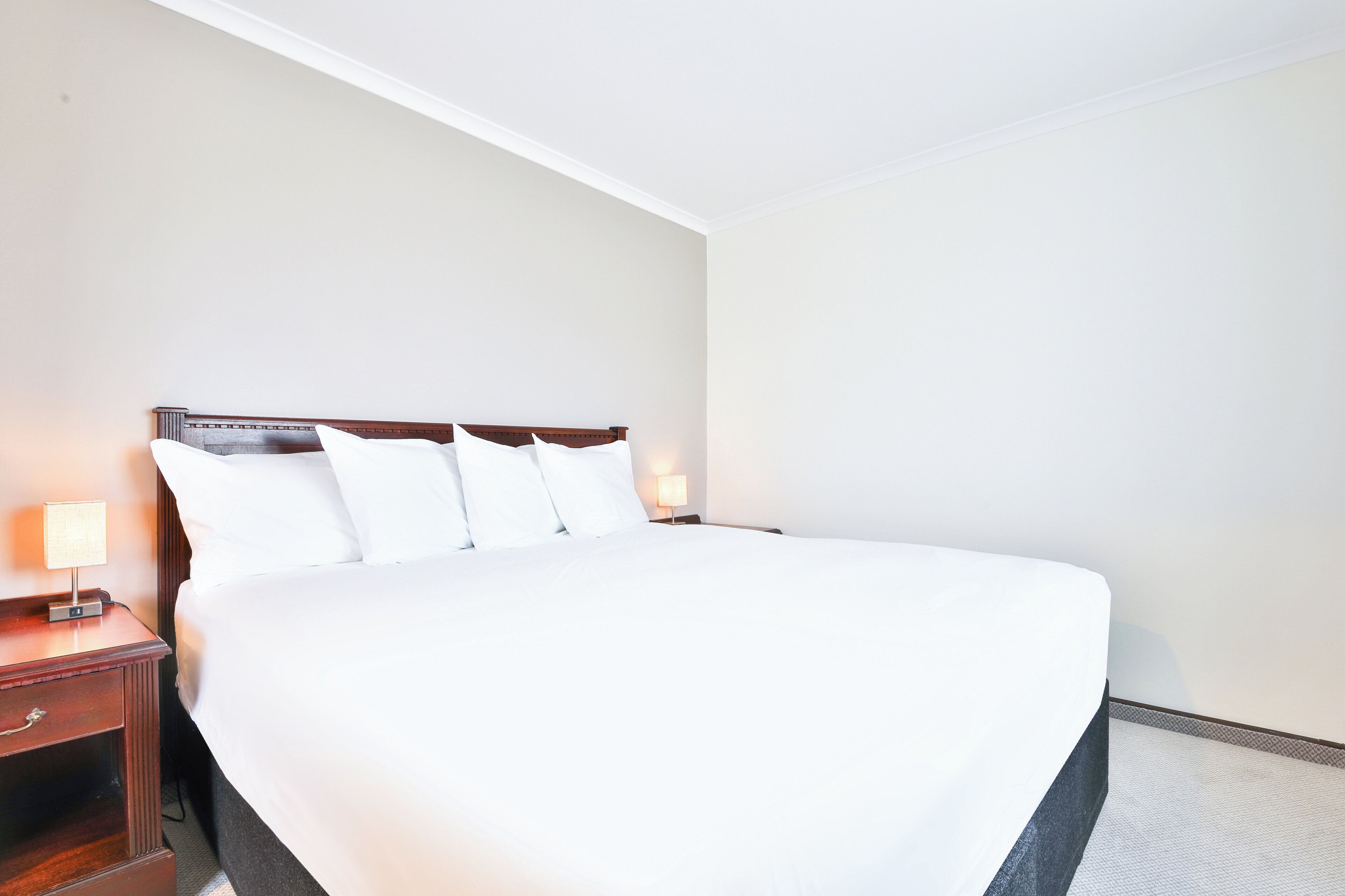 Ein ordentlich bezogenes Bett mit weißen Laken in einem Hotelzimmer.