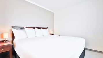 A neatly made bed with white linens in a hotel room.
