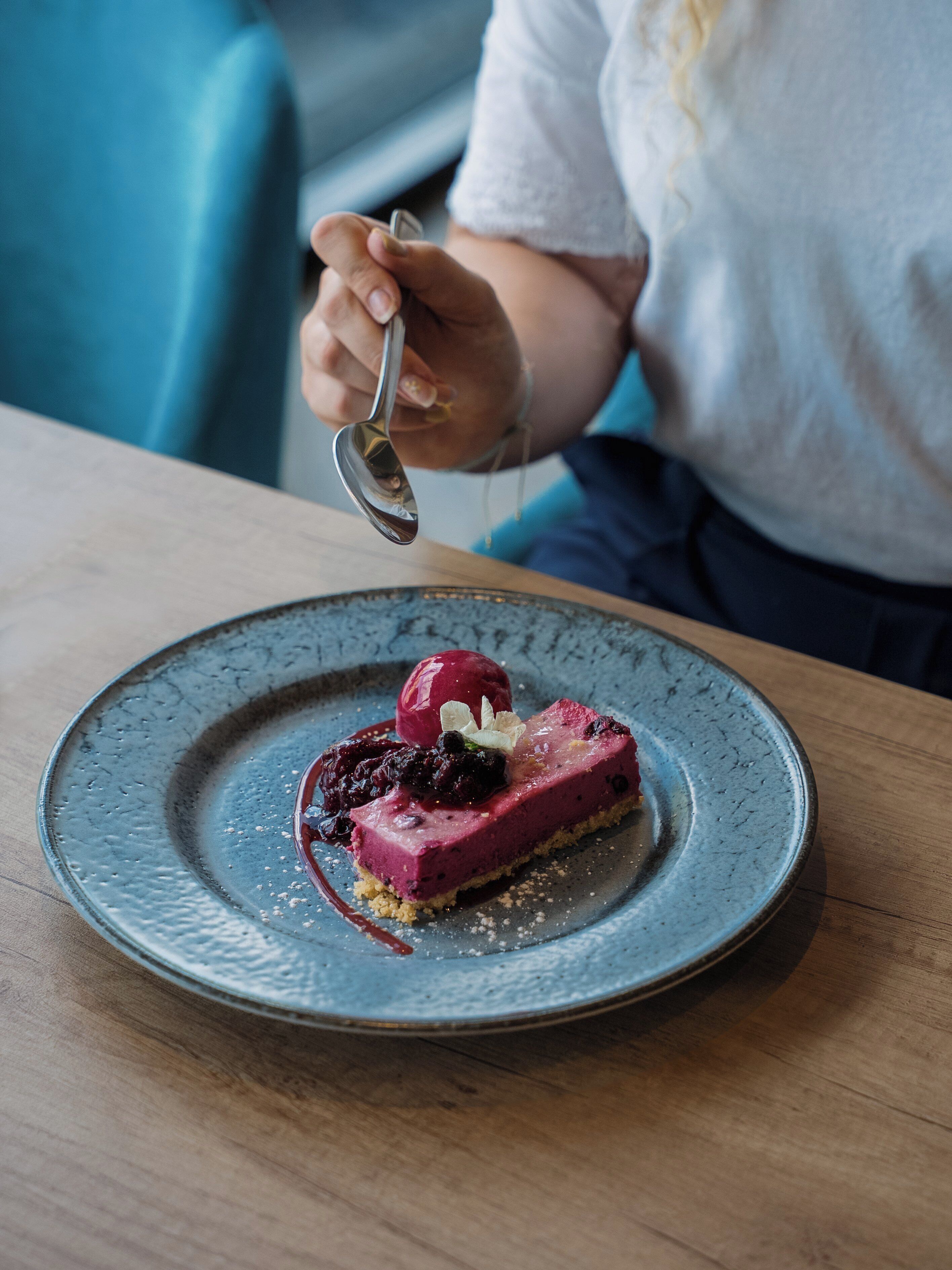 Un dessert servi dans une assiette en céramique, surmonté d’une boule de crème glacée et de quelques fruits rouges.