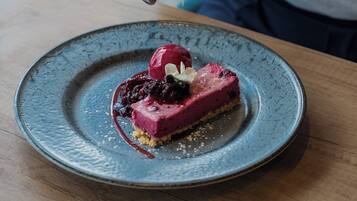 Un dessert servi dans une assiette en céramique, surmonté d’une boule de crème glacée et de quelques fruits rouges.